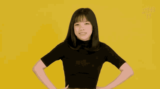 a girl stands with her hands on her hips in front of a yellow background that says jkt48 on it
