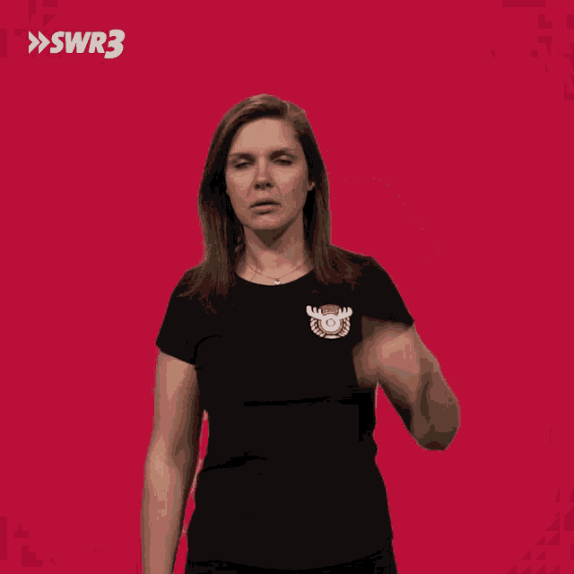 a woman in a black shirt is pointing at her head with a red background with swr3