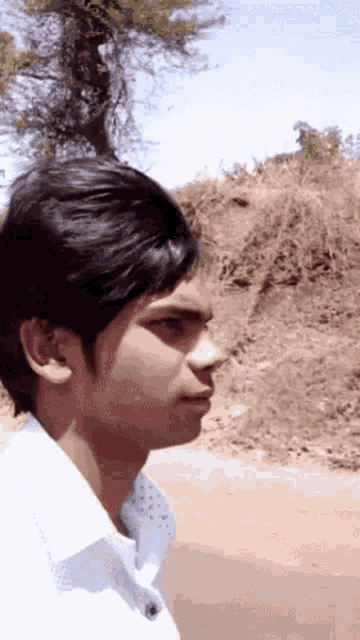 a young man in a white shirt is standing in front of a field