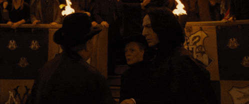 a man in a hat stands in front of a banner that says hogwarts on it