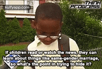 a young boy wearing glasses and a backpack is standing in a park .