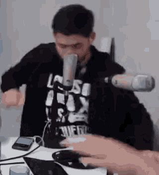 a man is sitting at a table with a microphone and a laptop .