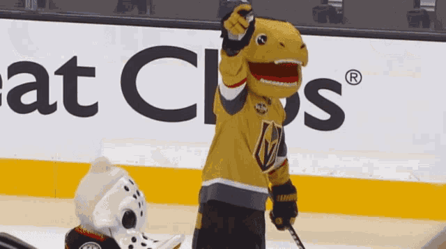 a mascot in a t-rex costume is holding a hockey stick