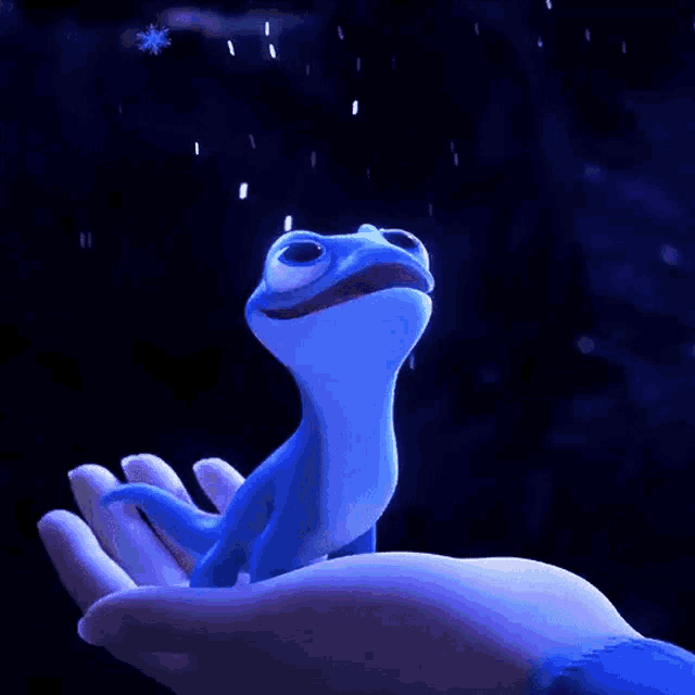 a person is holding a blue lizard in their hand in the rain .