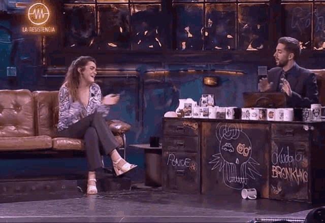 a woman in a zebra print shirt is sitting on a couch with her hands in the air .
