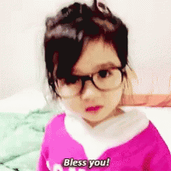 a little girl with glasses and a pink shirt says bless you