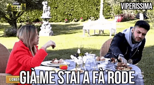 a man and a woman are sitting at a table with plates of food and a caption that says " viperissima "