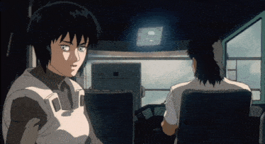 a man and a woman are sitting in a dark room and the woman is looking at something