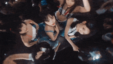 a group of women are standing in a circle in a dark room .