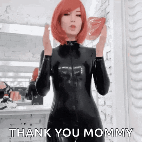 a woman in a black latex suit says thank you mommy in front of a mirror