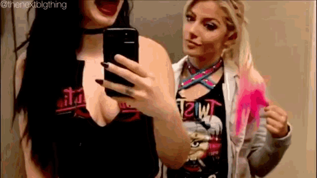 two women are taking a selfie together in a mirror . one of the women is wearing a choker .