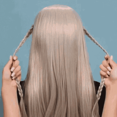 a woman with long blonde hair is braiding it in a braid