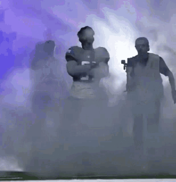 a football player with the number 5 on his jersey is walking through smoke