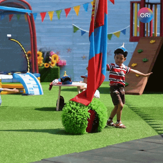 a boy in a party hat stands in a playground with the ori logo in the background