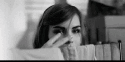 it is a black and white photo of a woman covering her face with her hand .