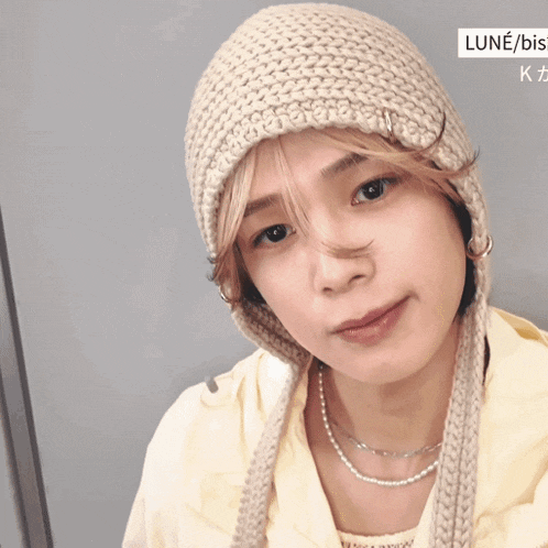 a woman wearing a knitted hat and a necklace with the word lune / bis on the bottom right