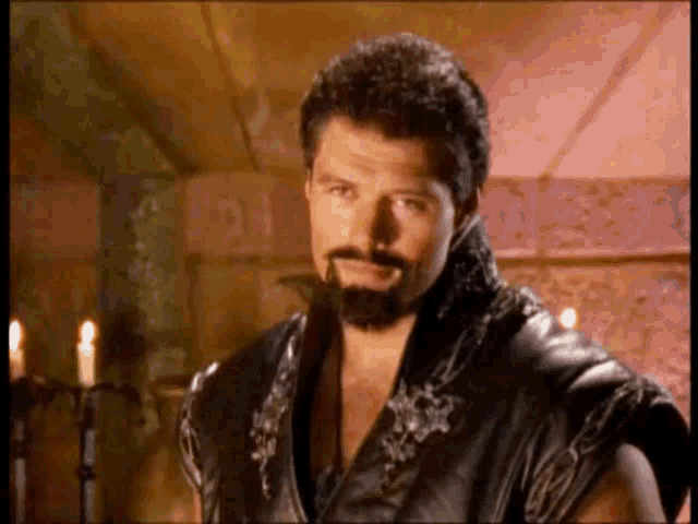 a man with a beard is wearing a black leather jacket .