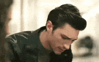 a man in a leather jacket is sitting at a table talking to a woman .