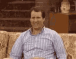 a man in a plaid shirt is sitting on a couch .