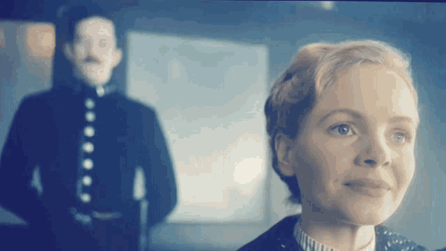 a man in a uniform stands behind a woman