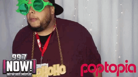 a man wearing green glasses stands in front of a poptopia sign