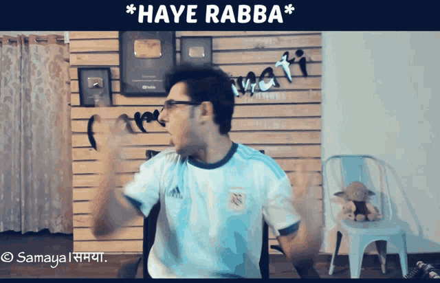 a man wearing an adidas shirt is dancing in front of a wooden wall