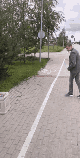 a man in a suit stands on a sidewalk next to a bike path