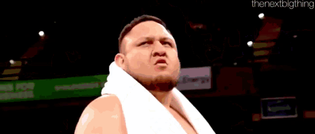 a man with a towel around his neck is standing in a ring and looking at the camera .