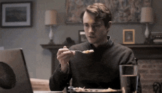 a man is sitting at a table with a plate of food and a laptop .