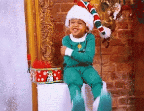 a little boy in a santa hat is sitting on a stool
