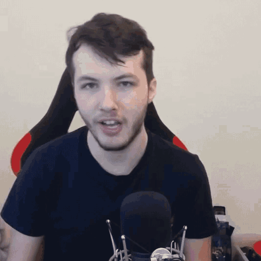 a man with a beard is sitting in a chair in front of a microphone and making a funny face .