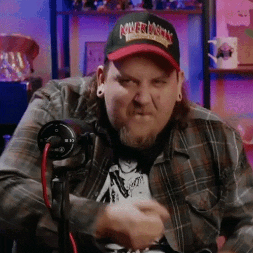 a man wearing a hat is sitting in front of a microphone and making a funny face .