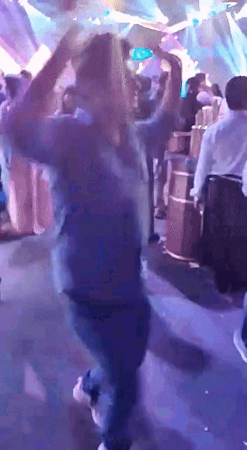 a group of people are dancing in a dark room with purple lights