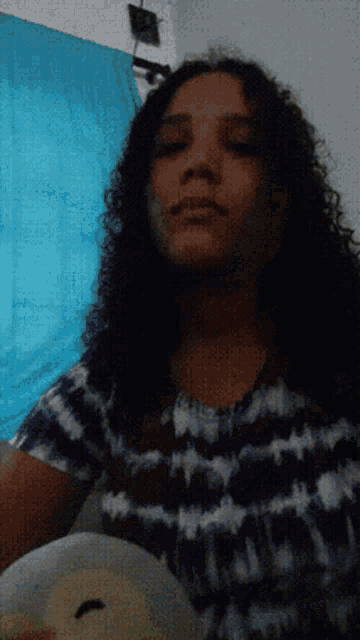 a woman with long curly hair is wearing a purple and white tie dye shirt