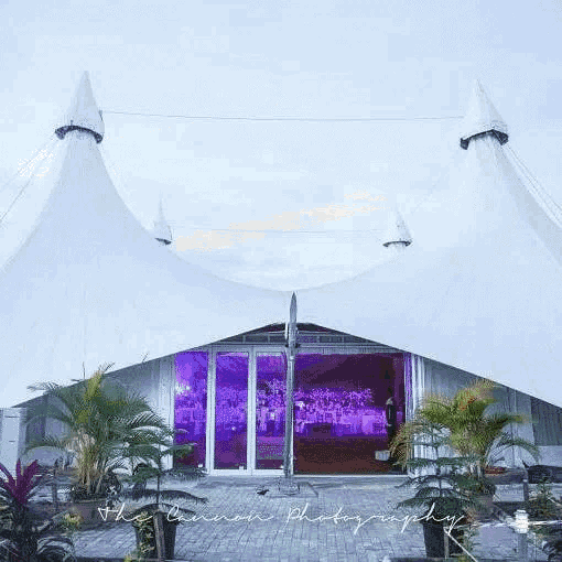 a large white tent with a lot of windows is in a dirt field