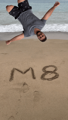 a man is laying on a beach with the number 8 written in the sand