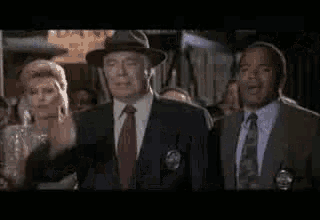three men in suits and ties are standing next to each other in front of a crowd .