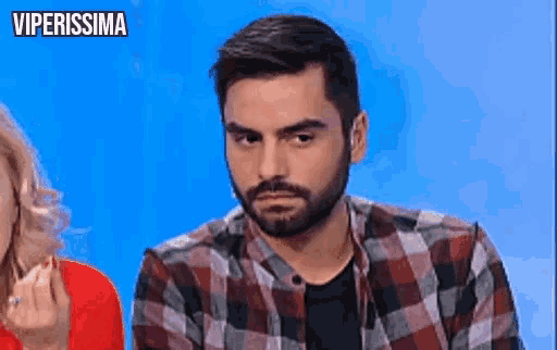 a man with a beard wearing a plaid shirt is sitting in front of a woman .