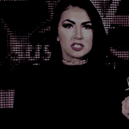 a woman in a black dress is holding a microphone in front of a screen .