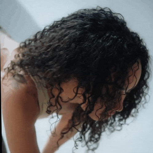 a woman with curly hair and a tattoo on her arm