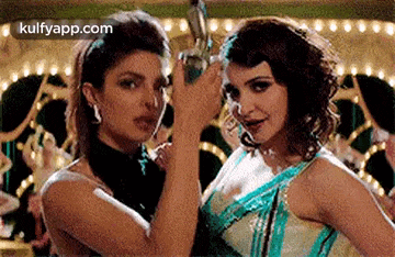 two women are standing next to each other in a room holding a trophy .