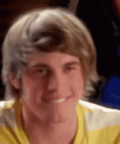 a young man in a yellow and white striped shirt is smiling and making a funny face .