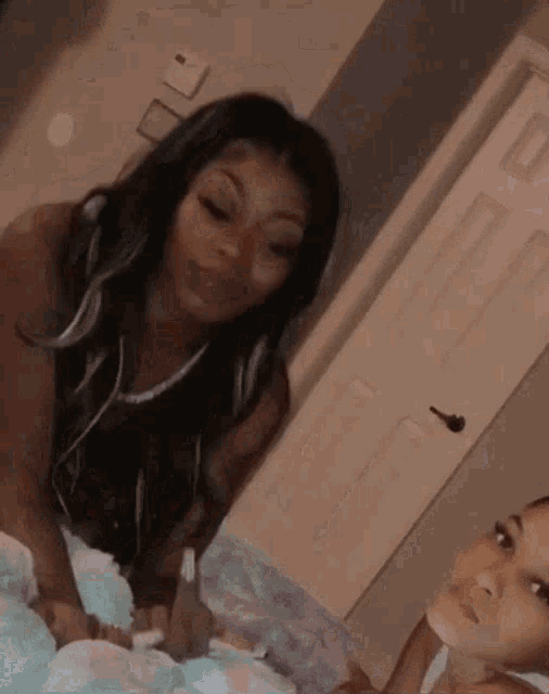 two women are standing next to each other in a room . one of the women is wearing headphones .