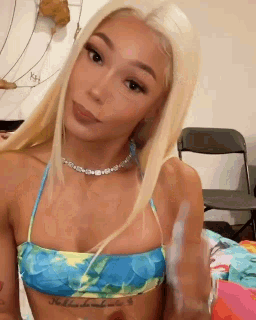 a woman in a blue and yellow bikini top has a tattoo on her chest that says nothing