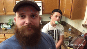 a man with a beard is standing next to another man in a kitchen