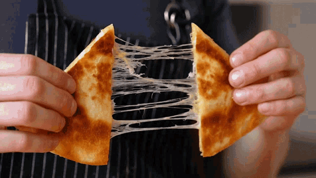 a person is holding a piece of bread that is being pulled apart