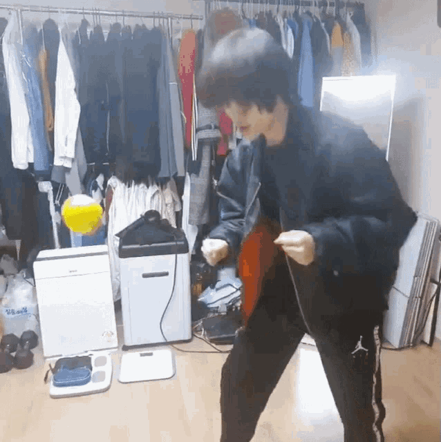 a person in a room with clothes hanging on a rack