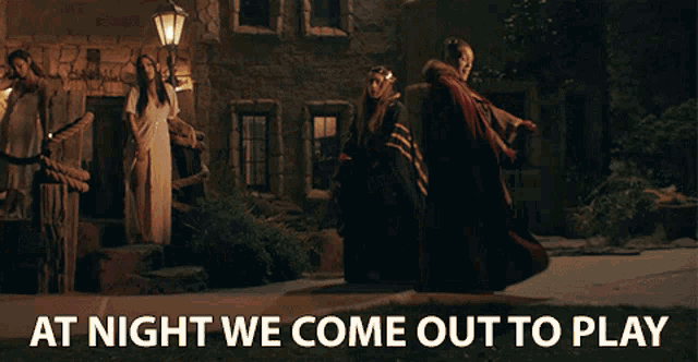 a group of people are standing in front of a castle with the caption at night we come out to play