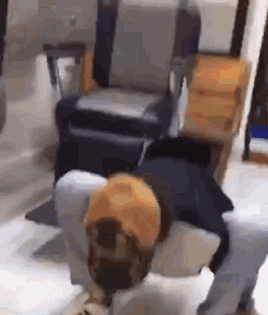 a man in a yellow hat is kneeling down in front of a barber chair .