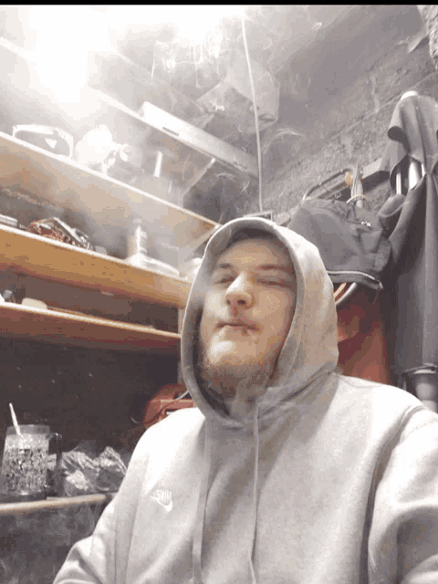 a man wearing a grey nike hoodie is smoking a cigarette